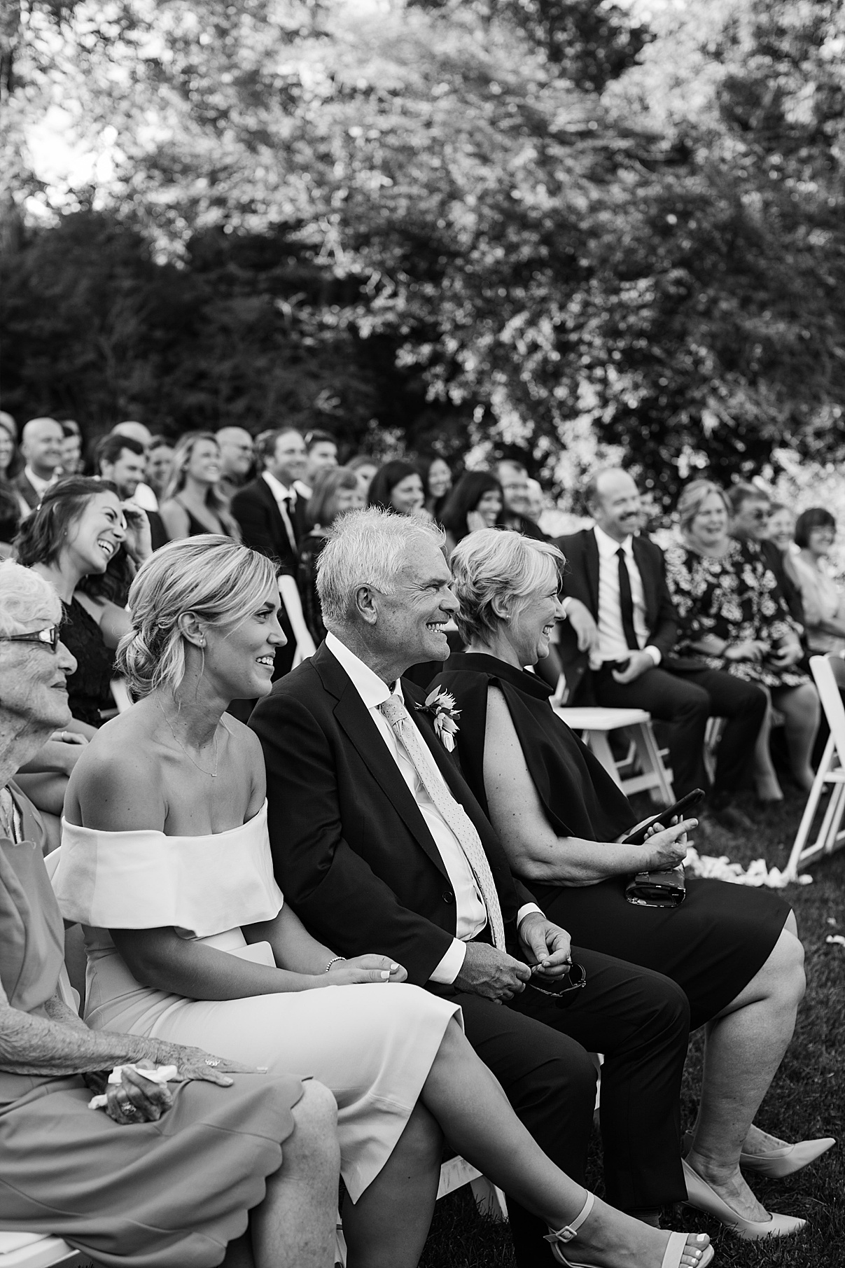 Black and white shot of guests smiling at wedding ceremony| Harding Waterfront Estate Wedding| Ontario wedding photographer| Toronto wedding photographer| 3 Photography | 3photography.ca