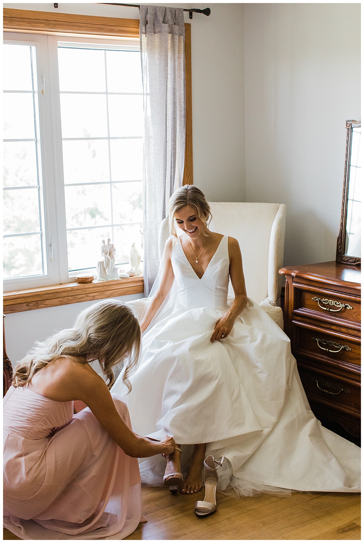 Bride sitting in chair by window while bridesmaid helps her put her bridal heels on| Georgetown, Ontario wedding| Toronto wedding photographer| 3photography