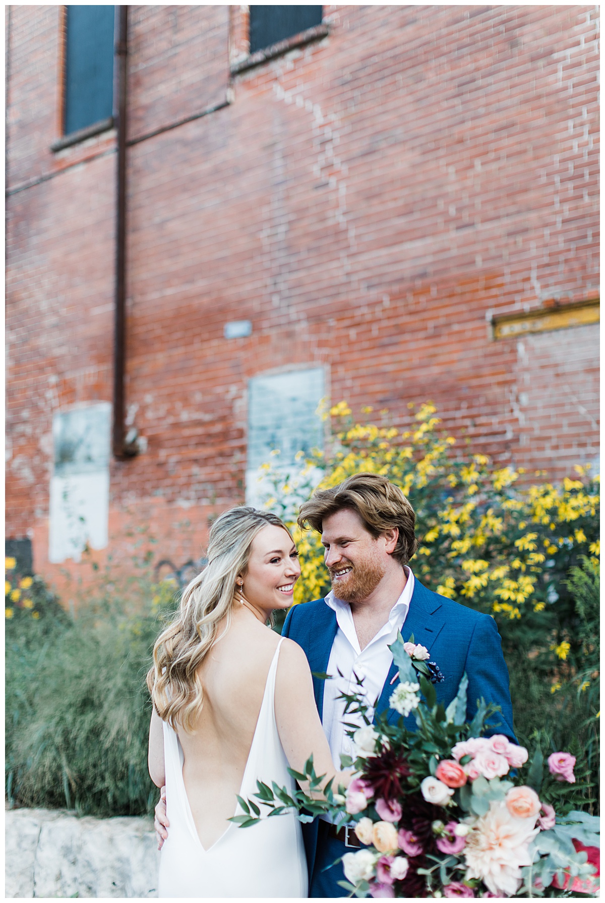 Bride in low back dress smiling with groom | wildflower wedding bouquet